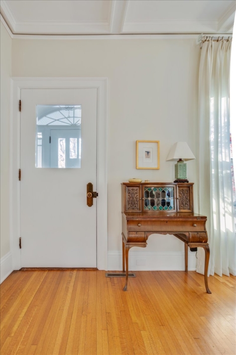 Entryway with antique credenza, small green lamp and artwork