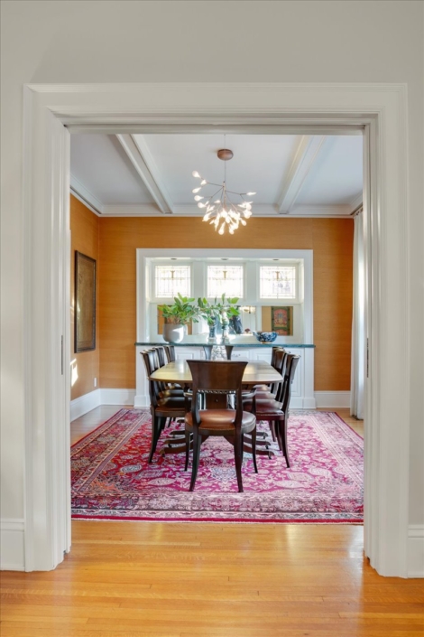 Dining room with traditional table and chairs and a modern light fixture. Global rug with reds and burnt umber walls