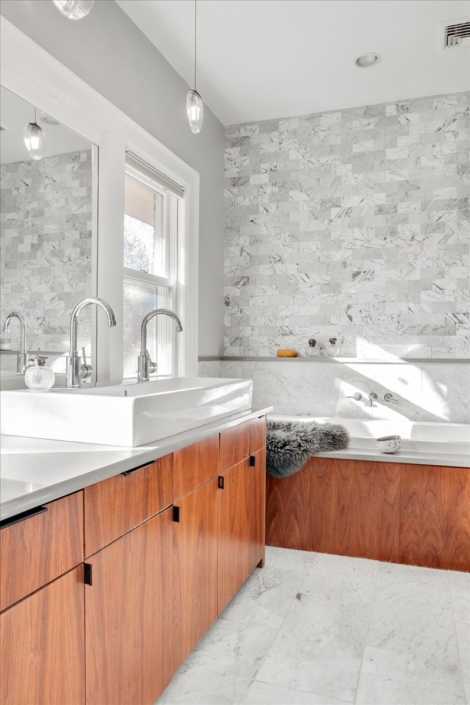 gray tiles bathroom with wood vanity, soaking tub, and hennepin made pendant lights