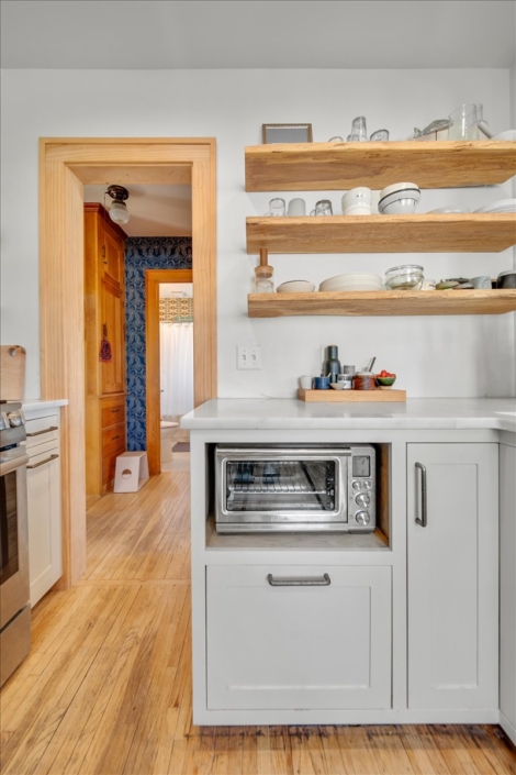 View of kitchen floating shelves and lower cabinets looking into the hallway