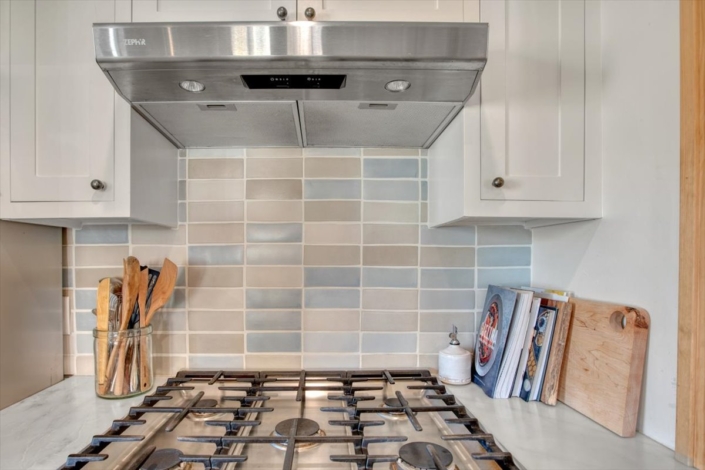 Handmade backsplash tile behind stove in blues and beiges.