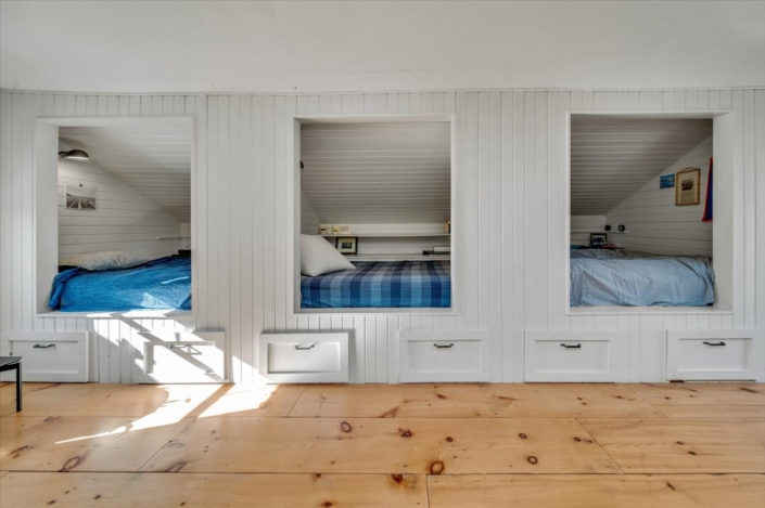 View into build-in bunk beds with white panelling and blue bedding