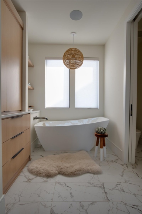 Soaking bathtub with rattan sphere light and small stool by sheepskin rug