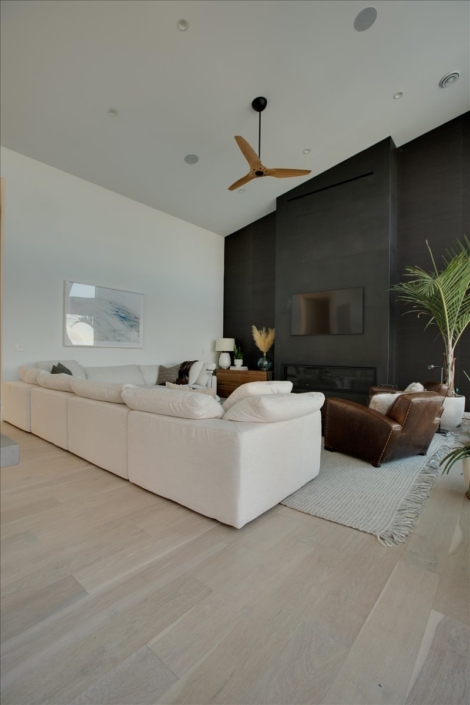 family room with cloud white sofa and steel fireplace wall, leather chair, large plant, and beach print art