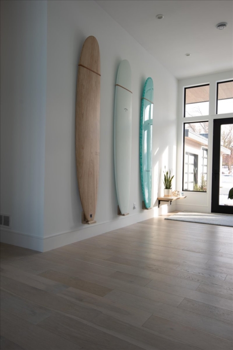 Surfboard entry wall of 3, natural, off white, and mint green with floating wood shelf and plant