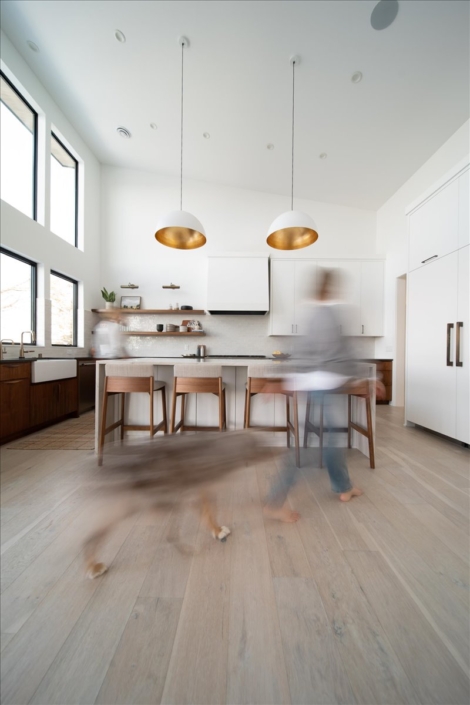 kitchen with white upper cabinets and wood lower cabinets. Island with five stools and a sconces with gold interior