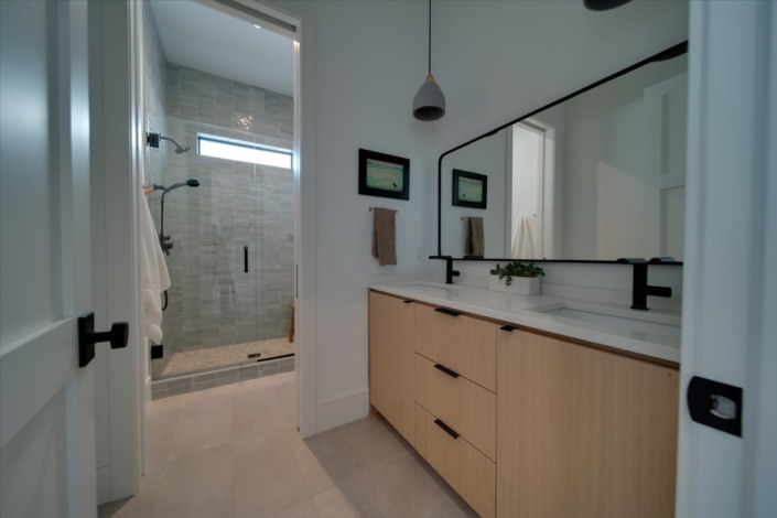 Bathroom vanity, mirror, towel, and accessories with view into tiled shower