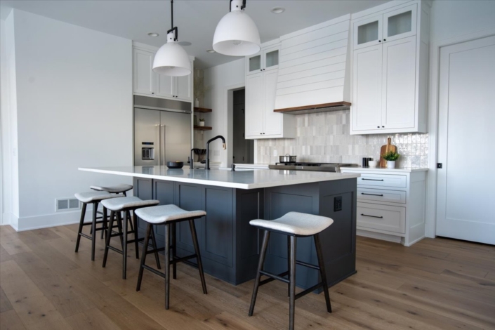 blue kitchen island with white cabinets, natural tile backsplash, wood floating shelves