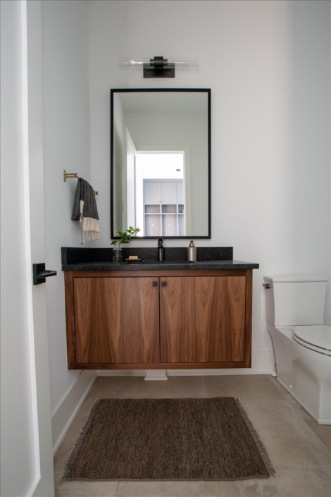 powder room floating vanity with black stone top and large rectangular mirror