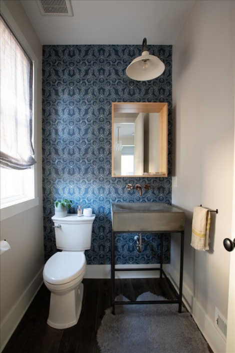 Bathroom with cement sink and blue wallpaper, wood mirror