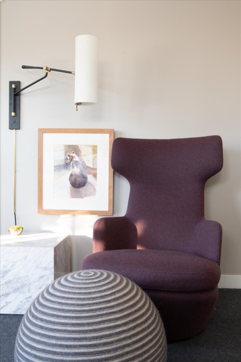 Purple chair with sphere ottoman, art, and unique sconce