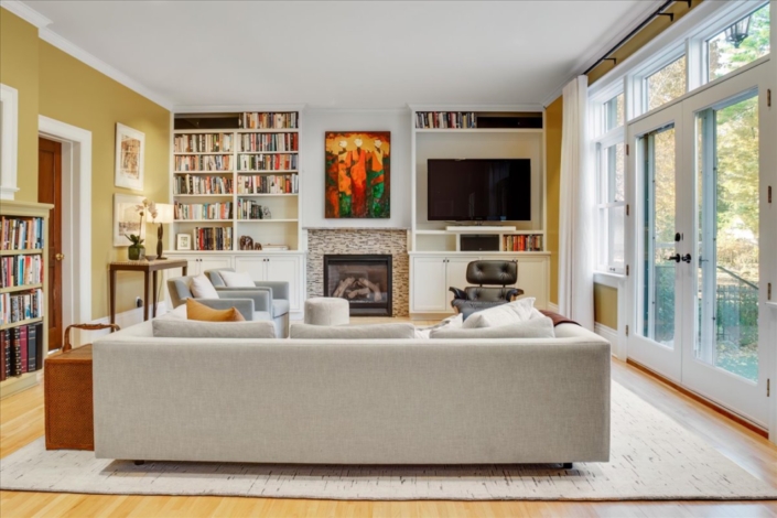 Family room with couch, swivel side chairs, Eames chair, fireplace with bookcase and art