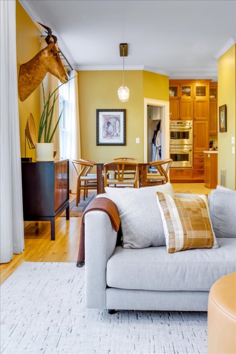 Natural couch with layered throw and pillow and view into dining area