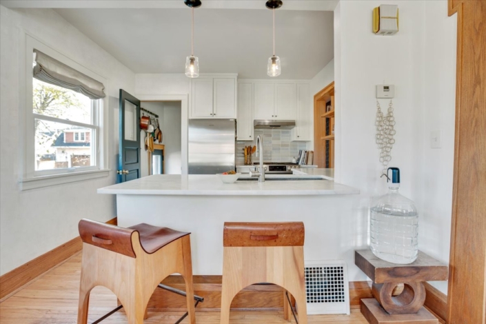 View into kitchen with sconces and wood stools with leather seat