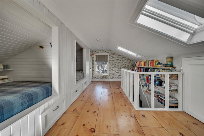 Upstairs built-in bunk room and white railing with bookshelf half wall