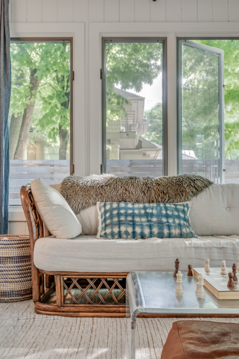 Porch couch with sheepie and blue print pillow. Chess board in the forefront