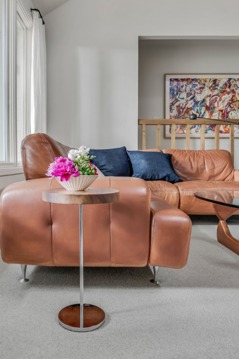 vinatage couch with navy pillows and a small side table with flowers, colorful art in the background