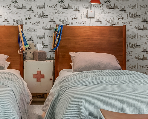 twin beds with red sconce and wallpaper