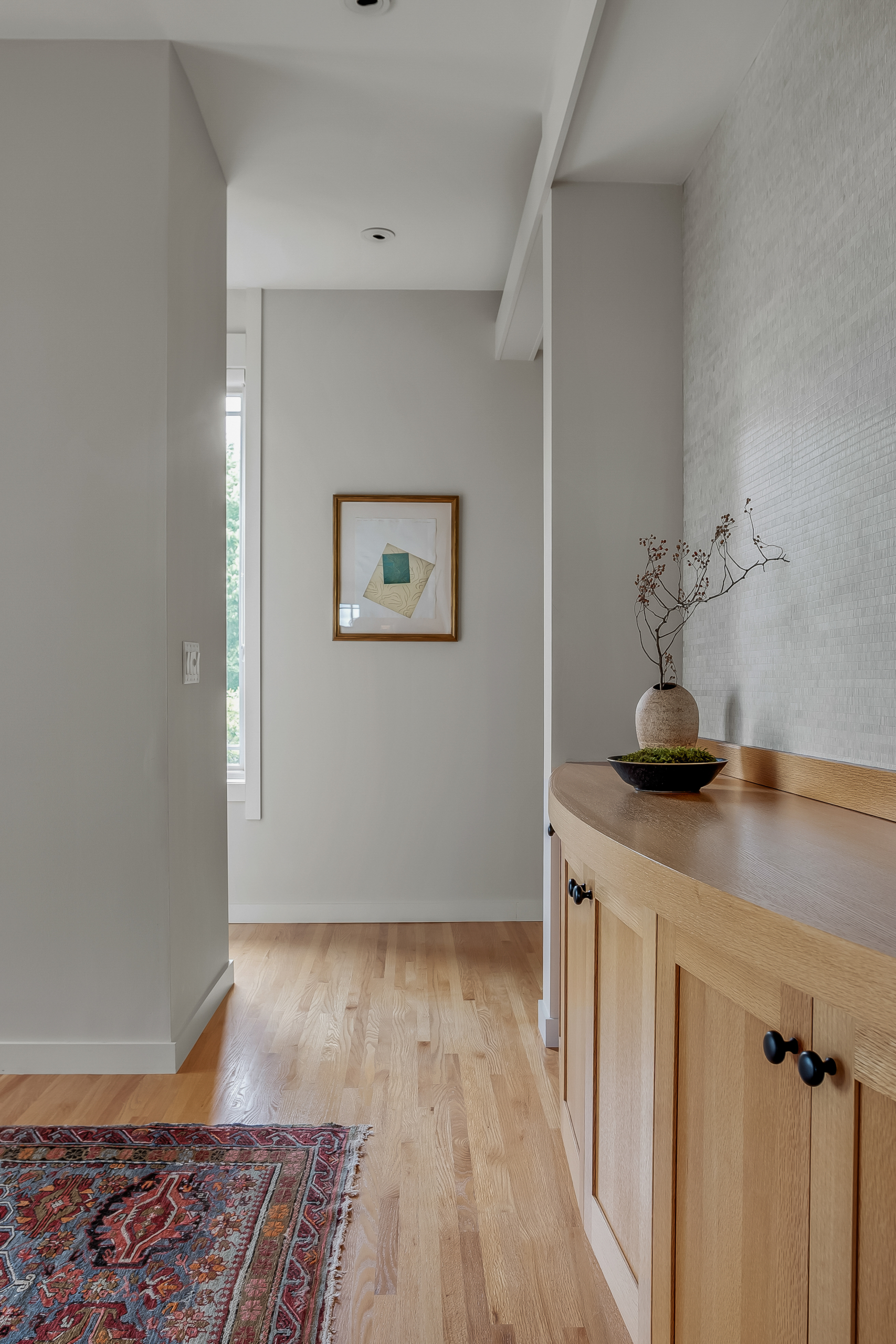 Hallway with art and vase and global rug